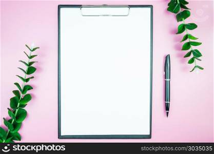 Women&rsquo;s stylish table. Workspace with blank white paper free space and pen in desk with flowers on pink pastel background for magazines, websites, media, Instagram. Flat lay, top view. Women&rsquo;s stylish table. Workspace with blank white paper free spa