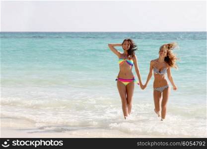 Women run on beach. Beautiful fit women in bikni run on tropical beach