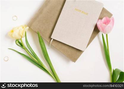 Women’s flat lay with notebooks and spring flowers tulips on a white background