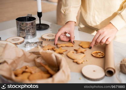 Women’s hands lay out curly ginger cookies on parchment. Festive table decor. A woman’s hands shift ginger cookies from paper to a box