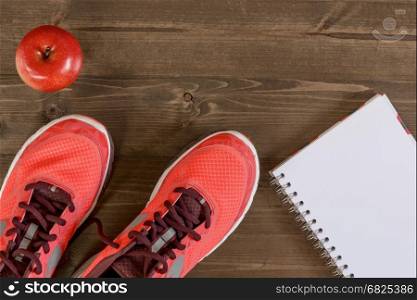 Women's shoes and a notebook for recording sporting achievements on the wooden floor