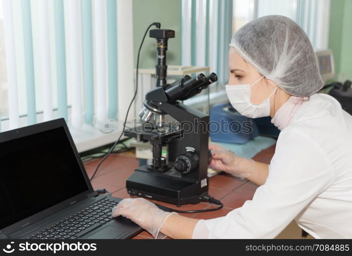 Women scientists exploring the biological sample by modern electron microscope in a laboratory