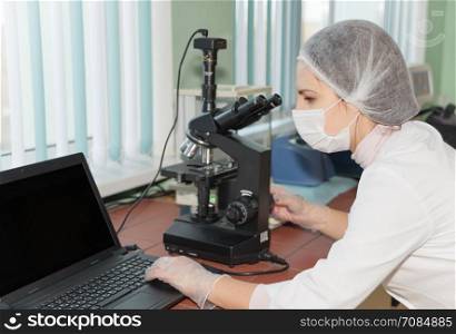 Women scientists exploring the biological sample by modern electron microscope in a laboratory