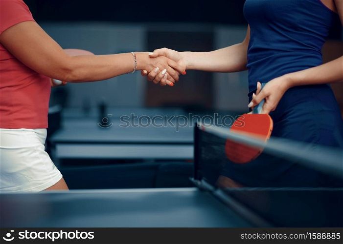 Women shake hands before table tennis match, ping pong players. Friends playing table-tennis indoors, sport game with racket and ball, active healthy lifestyle. Women shake hands before table tennis match