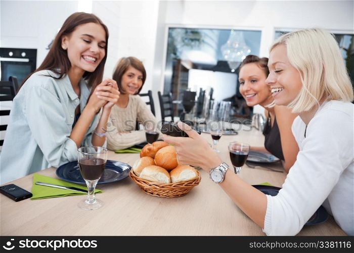 Women showing something to her friends on mobile phone at dining table - Shallow Depth of field critical focus on phone.