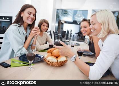 Women showing something to her friends on mobile phone at dining table - Shallow Depth of field critical focus on phone.