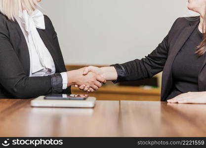 women sitting table shaking hands