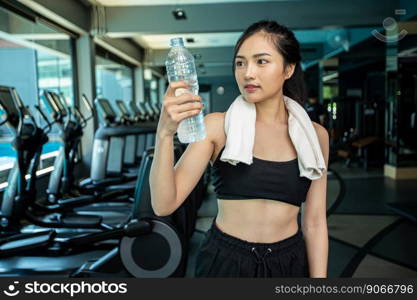 Women stand and relax after exercising, holding and looking at the water bottle.