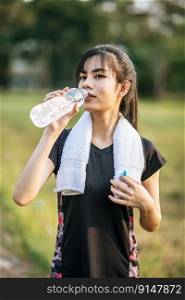 Women stand to drink water after exercise. Selective focus.
