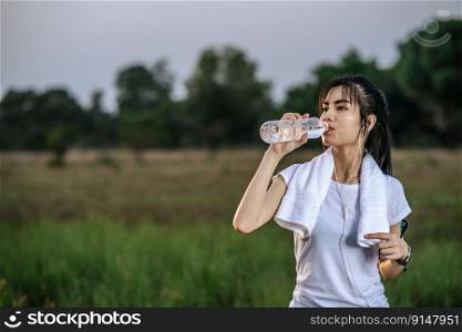 Women stand to drink water after exercise. Selective focus.