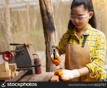 Women standing builder wearing checked shirt worker of construction site hammering nail in the wooden board