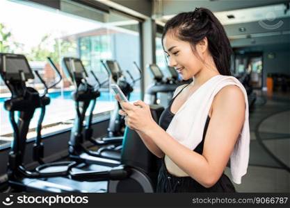 Women standing playing the phone happily in the gym.
