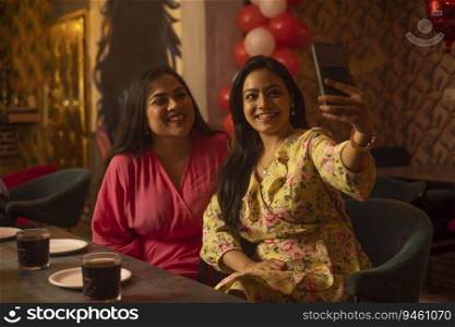 Women taking selfie while sitting together at restaurant
