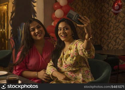 Women taking selfie while sitting together at restaurant