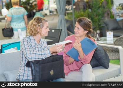 Women talking, holding bag and clipboard
