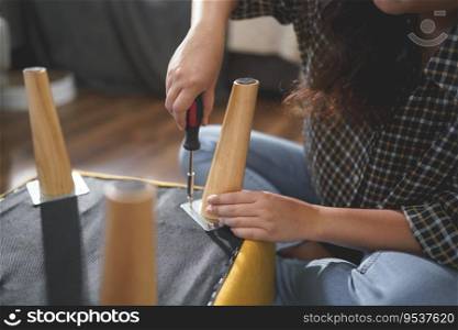 Women tighten screw with screwdriver equipment for repairing leg of chair and assembling furniture.