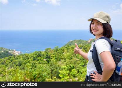 Women tourist on viewpoint at Koh Tao. Women tourist with a backpack wear cap raise thumbs up for the beautiful nature landscape blue sea and sky from high scenic viewpoint at Koh Tao, Surat Thani, Thailand