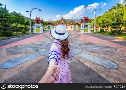 Women tourists holding man&rsquo;s hand and leading him to Ho kham luang northern thai style in Royal Flora ratchaphruek in Chiang Mai,Thailand.