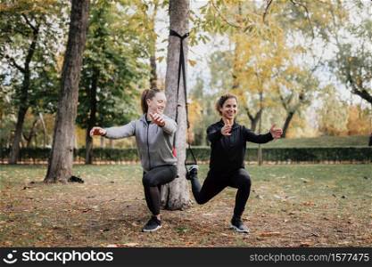 Women training together with trx outside in the park.. Women training with trx outside in the park.