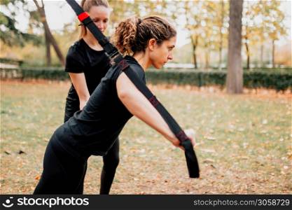 Women training together with trx outside in the park.
