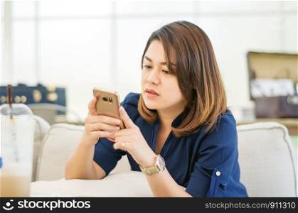 Women using a smartphone in a coffee shop, soft focus.