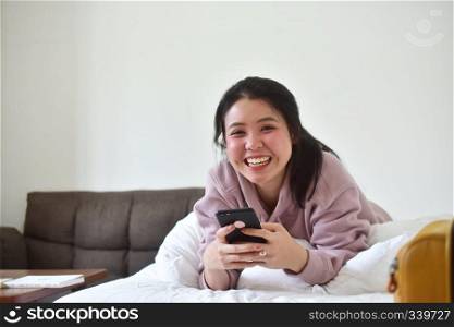 Women using mobile smartphone is ion bedroom