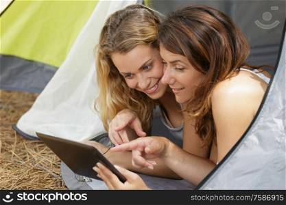 women using tablet while inside the tent