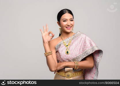Women wearing Thai clothes and hand symbolizing OK