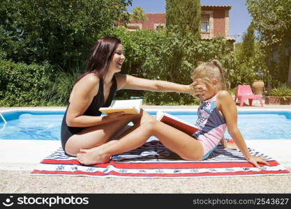 women with books sitting by pool