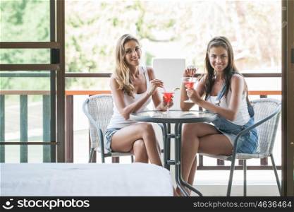 Women with cocktails in cafe. Two beautiful women having fun with cocktails in cafe