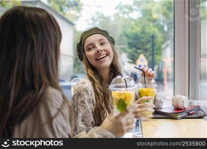 women with fresh drinks talking cafe
