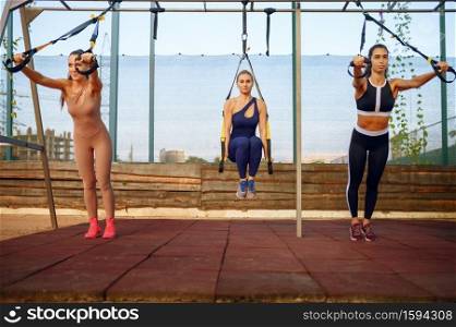 Women with perfect body on sports ground, outdoors group training. Female athletes in sportswear, team fitness workout, teamwork. Women with perfect body, outdoors group training