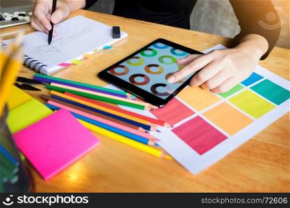 women working as fashion designer choosing on colour chart for clothes in digital tablet at workplace studio