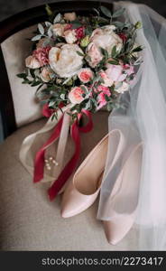 Womens elements of the wedding wardrobe in anticipation of the wedding.. Bouquet, shoes and jewelry of the bride on the chair 3788.