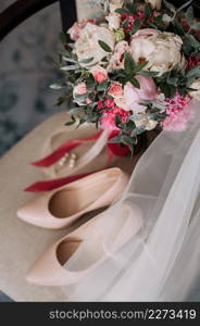 Womens elements of the wedding wardrobe in anticipation of the wedding.. Bouquet, shoes and jewelry of the bride on the chair 3789.