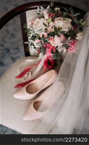 Womens elements of the wedding wardrobe in anticipation of the wedding.. Bouquet, shoes and jewelry of the bride on the chair 3790.