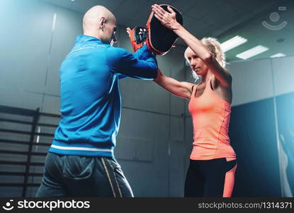 Womens self-defense workout with personal trainer, fighting training in gym, martial art