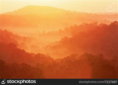 Wonderful autumn mountain in the morning mist, glowing sunrise shines onto autumn forest and mountain range in the background. Soft focus.