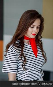 Wonderful girl with long thick hair close-up.. A large portrait of a beautiful girl in a striped blouse and a red scarf aroun