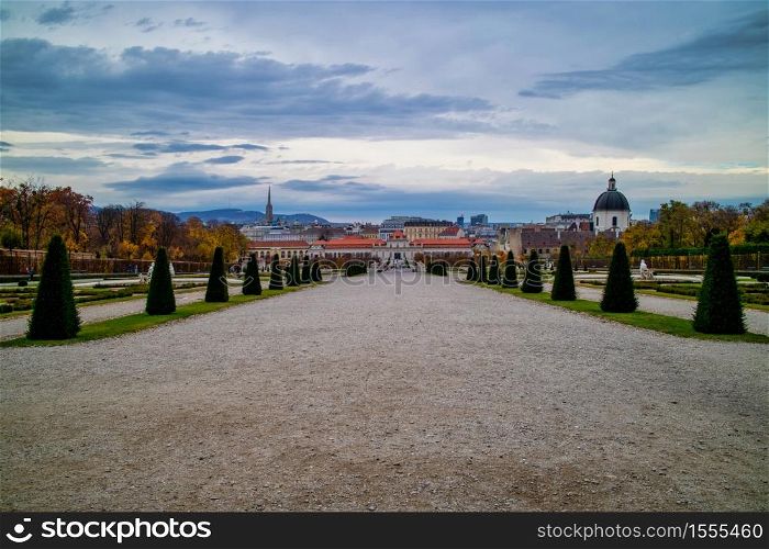 Wonderful landscape with wide main walking alley before Unteres Belvedere with regular planting of trees and plants in Vienna, Austria on a background of cloudy sky.. The main walking alley before Unteres Belvedere in Vienna on a background of cloudy sky.