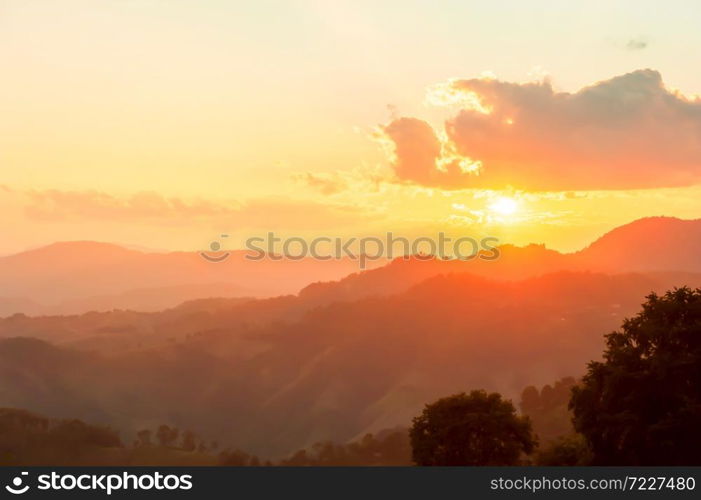 Wonderful mountain view at sunset, glowing sun setting behind the clouds and mountain range. Positive emotions concept. Soft focus.