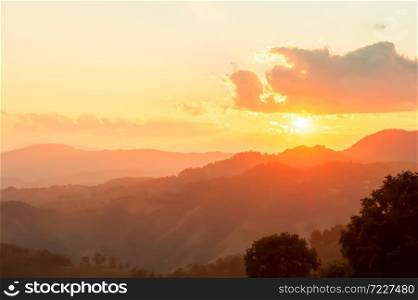 Wonderful mountain view at sunset, glowing sun setting behind the clouds and mountain range. Positive emotions concept. Soft focus.