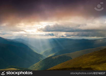 Wonderful panorama of the mountains. The sunbeams penetrates through the clouds in the middle of the valley.. Sun rays over valley