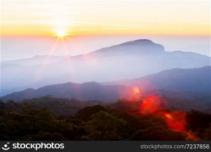 Wonderful sunrise over the mountain peak, magical star shape ray from the sun with lens flare. Doi Inthanon, Chiang Mai, Thailand.