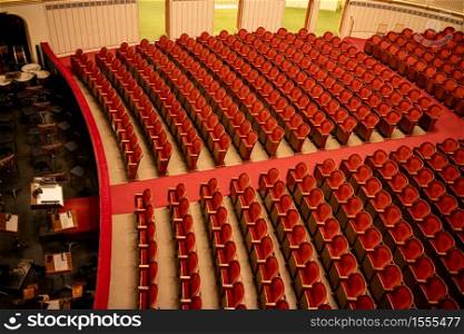 Wonderful view of the theatre concert hall of Vienna State Opera auditorium in Vienna, Austria - empty parterre with red seats in the rows without people and part of the orchestra pit.. Red seats in the rows without people in Vienna State Opera auditorium.