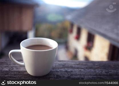 wonderful weekend - a cup of coffee on a background of a house in the mountains