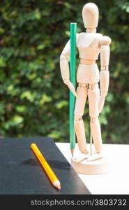 Wood artist mannequin standing with colour pencil, stock photo