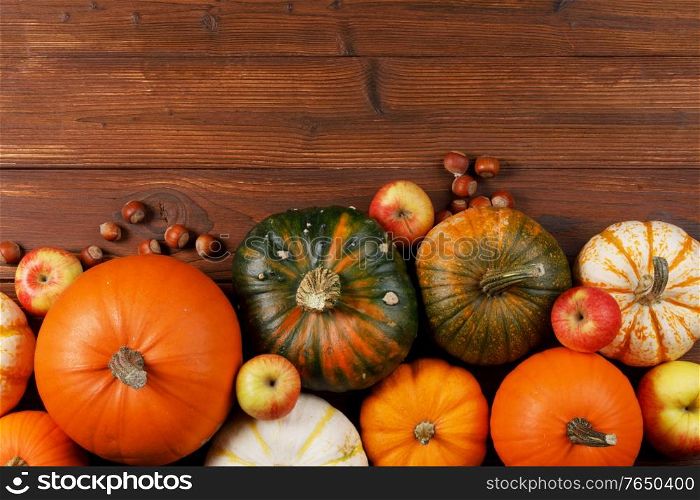 Wood background with pumpkin, apples and nuts. Copy space for text. Wood background with pumpkin