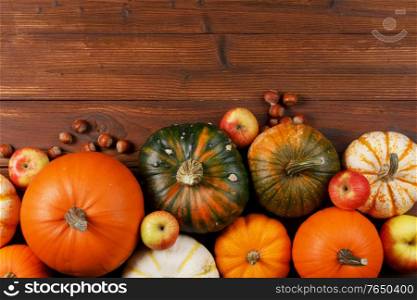 Wood background with pumpkin, apples and nuts. Copy space for text. Wood background with pumpkin