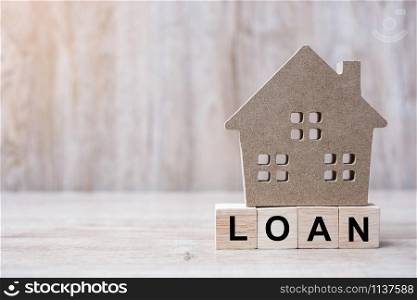 Wood block with LOAN text and house model on wooden background. Banking, real estate, Property investment, home mortgage, financial and savings concepts
